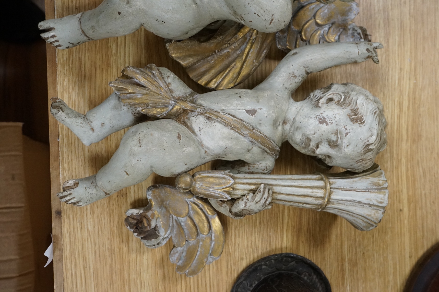 A pair of cream painted and parcel gilt carved wood putti candleholders, 32cm high